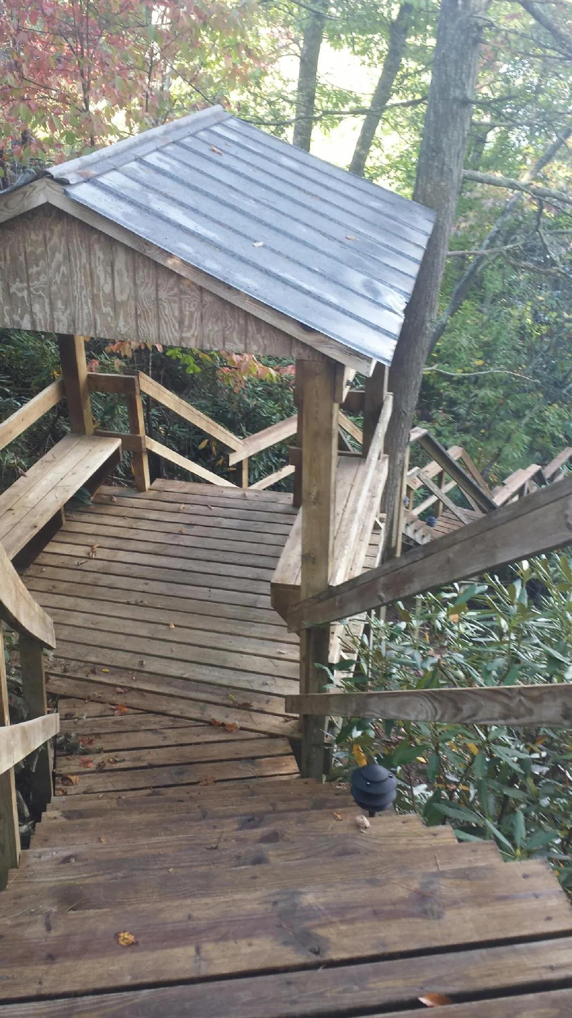 Metal roofed shelter over wooden steps on a wooded walkway — Skylight Repair & Installation work by our crew in Hempstead